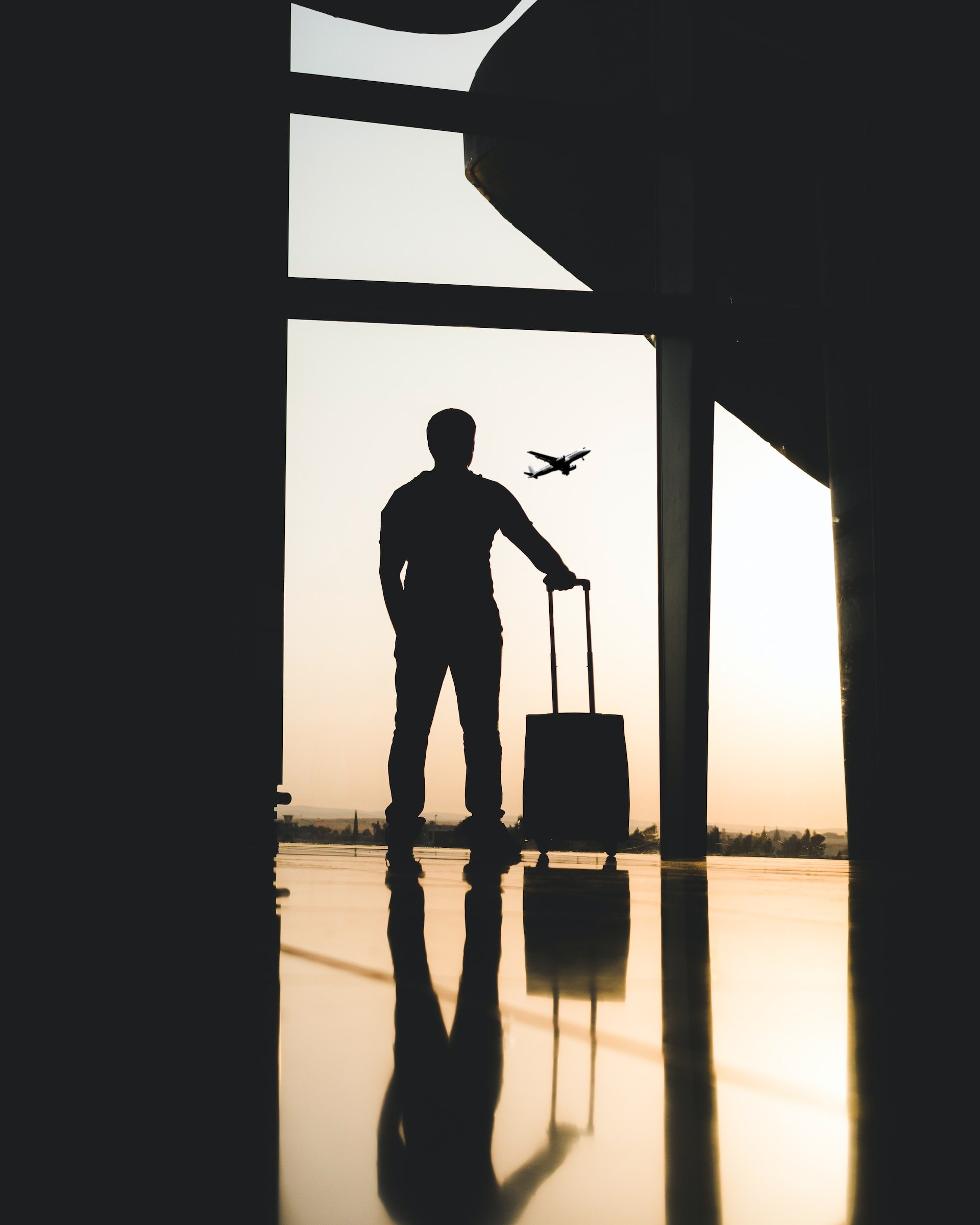 Reiziger met koffer op het vliegveld met een vliegtuig op de achtergrond