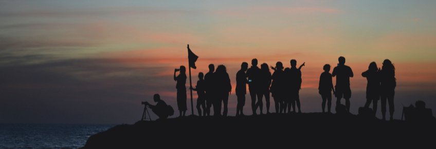 Groep mensen bij zonsondergang aan de kust